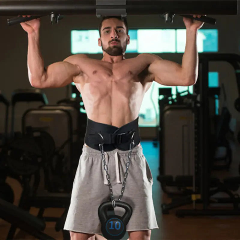Man performing pull-ups with a weight belt and kettlebell in a gym setting, from ghg global powerhouse.