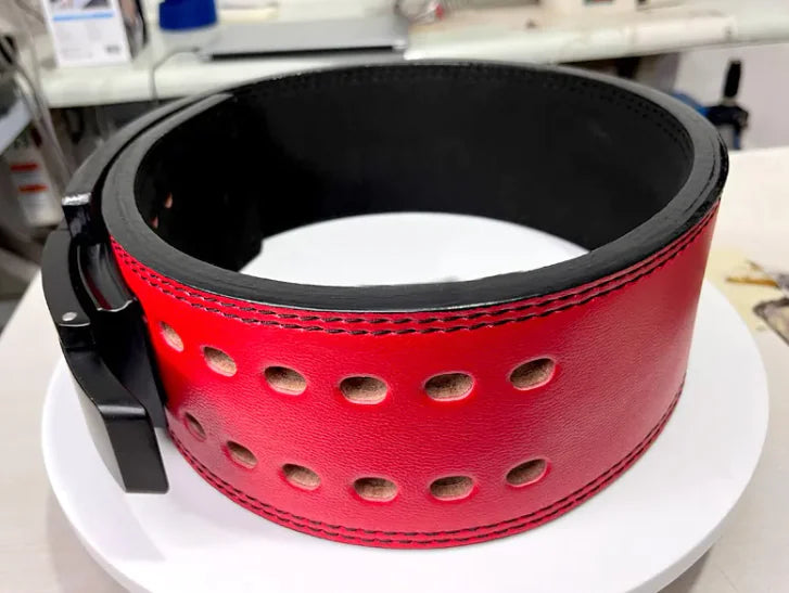 Red leather belt with black trim on a white surface, from ghg global powerhouse.